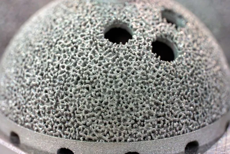 Close-up of the porous lattice surface on a 3D printed titanium acetabular cup