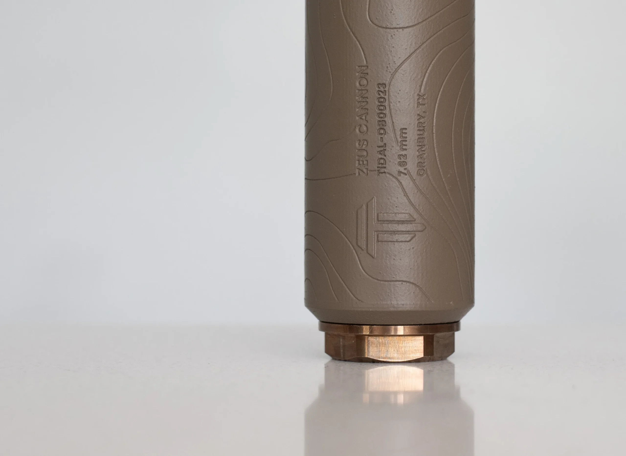Cerakoted 7.62mm titanium suppressor with a topographic pattern and bronze mount, studio shot